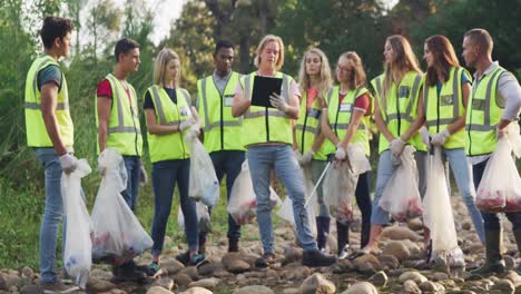 adultos de mediana edad con chalecos amarillos voluntarios durante el día de limpieza del río