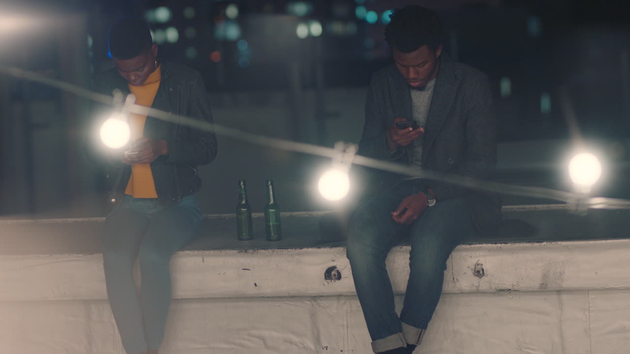 아프리카계 미국인 친구들이 스마트폰을 사용하여 소셜 미디어 메시지를 검색하고 옥상 파티에 관심이 없다는 것을 보여줍니다. 밤에 어울리는 반사회적 청소년