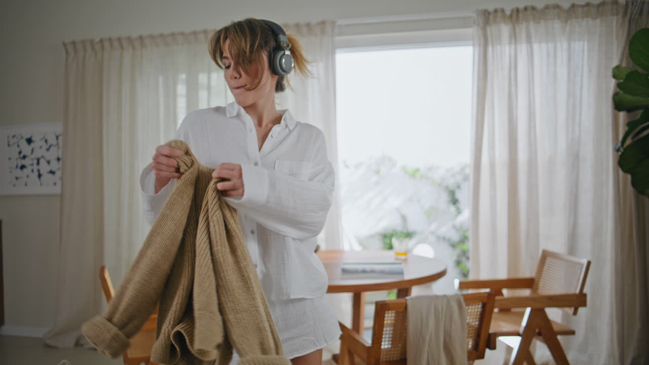 Domestic girl dancing music in headphones at weekend morning. Woman moving
