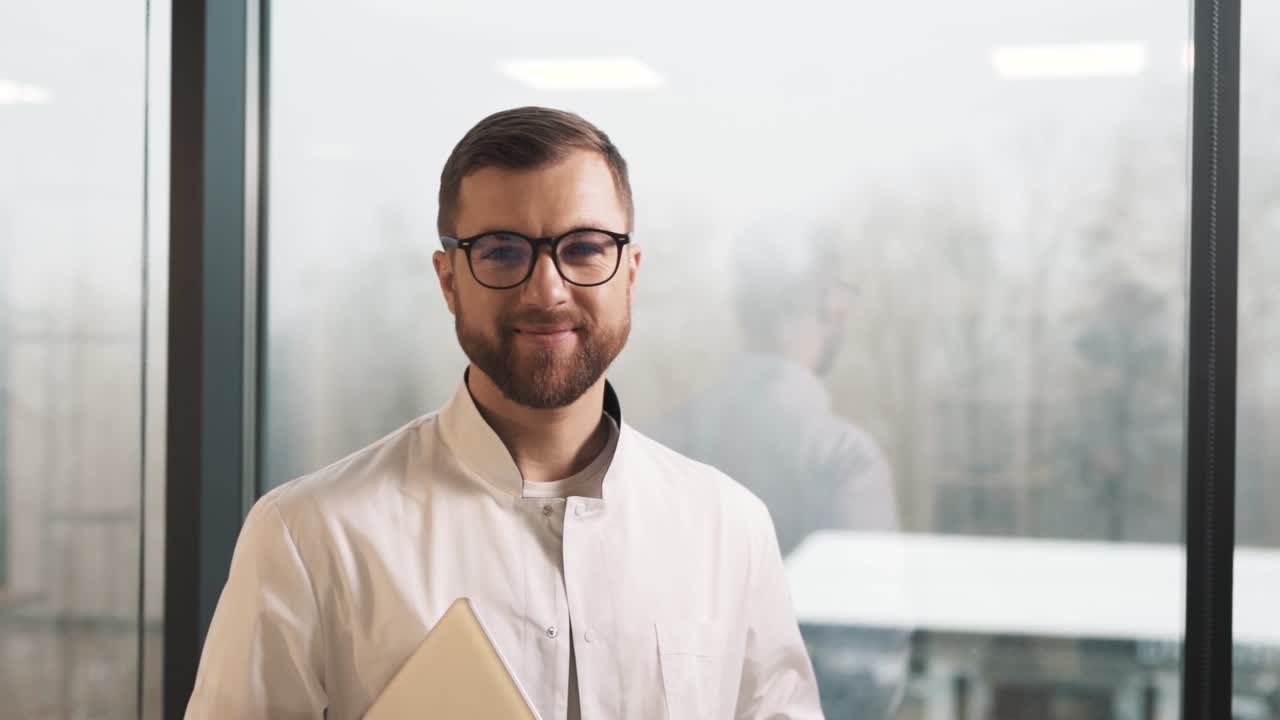 retrato de un joven médico agradable y atractivo con una bata blanca y una camisa, sonriendo con una apariencia caucásica