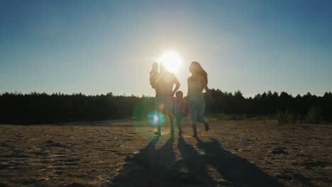 Glückliche-Familieneltern-Und-Zwei-Söhne,-Die-Bei-Sonnenuntergang-über-Den-Sand-Laufen