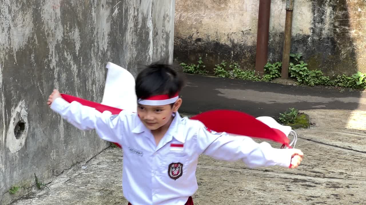Rallentatore di uno scolaro che corre e sventola la bandiera indonesiana per la celebrazione della festa dell'indipendenza