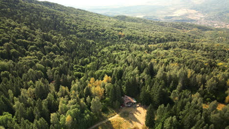 Vista-Aérea-Circular-Del-Bosque-De-Vitosha-Con-Cabaña-Para-Caminatas-Y-La-Ciudad-Al-Fondo.