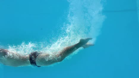 fit man diving underwater in swimming pool