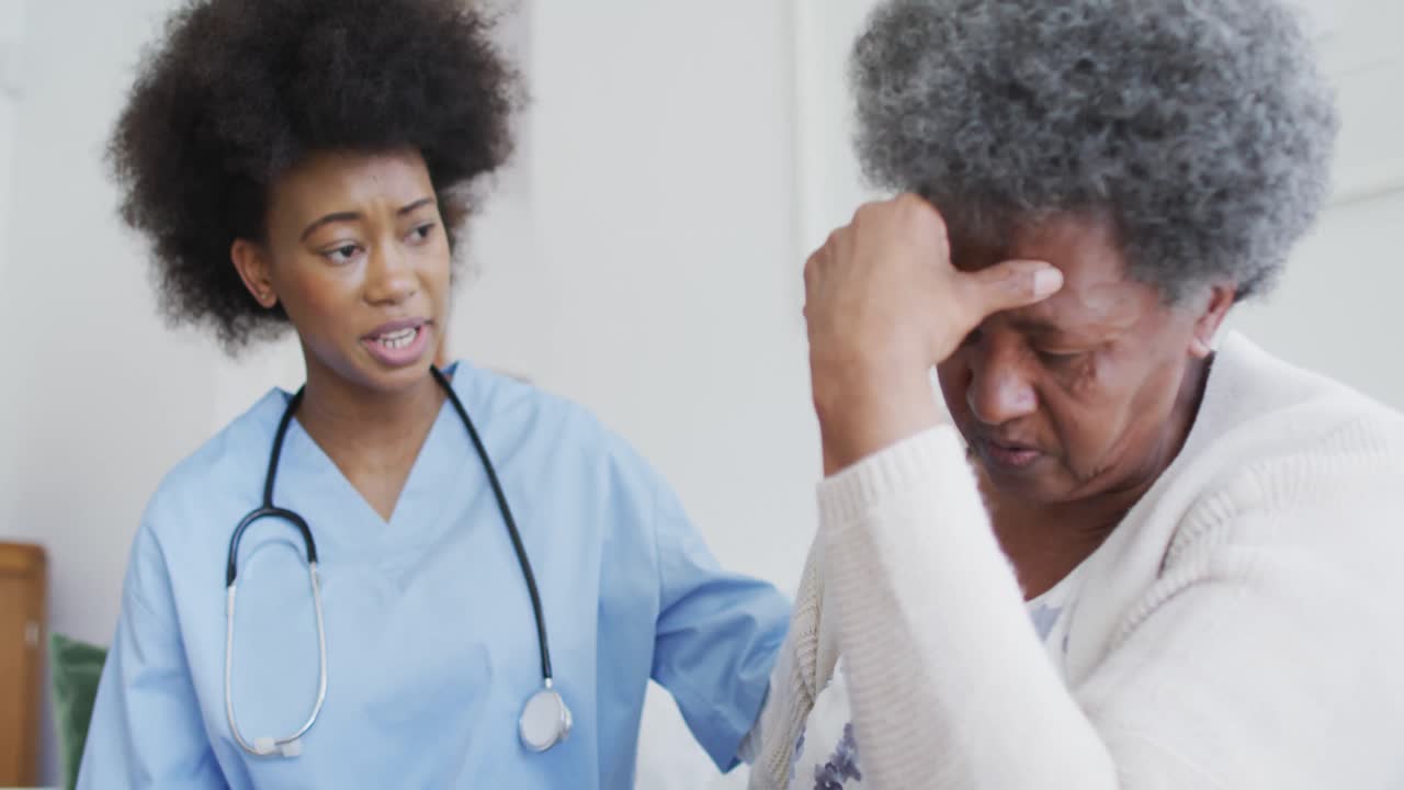 Caring african american female doctor and sad senior female talking