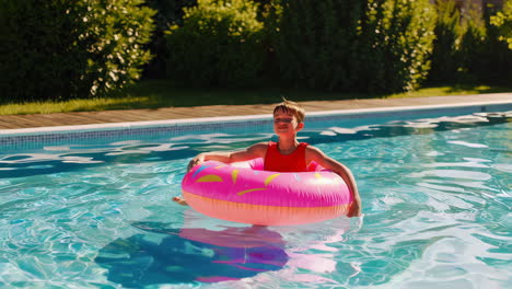 young boy enjoying a summer day in the swimming pool with an inflatable ring