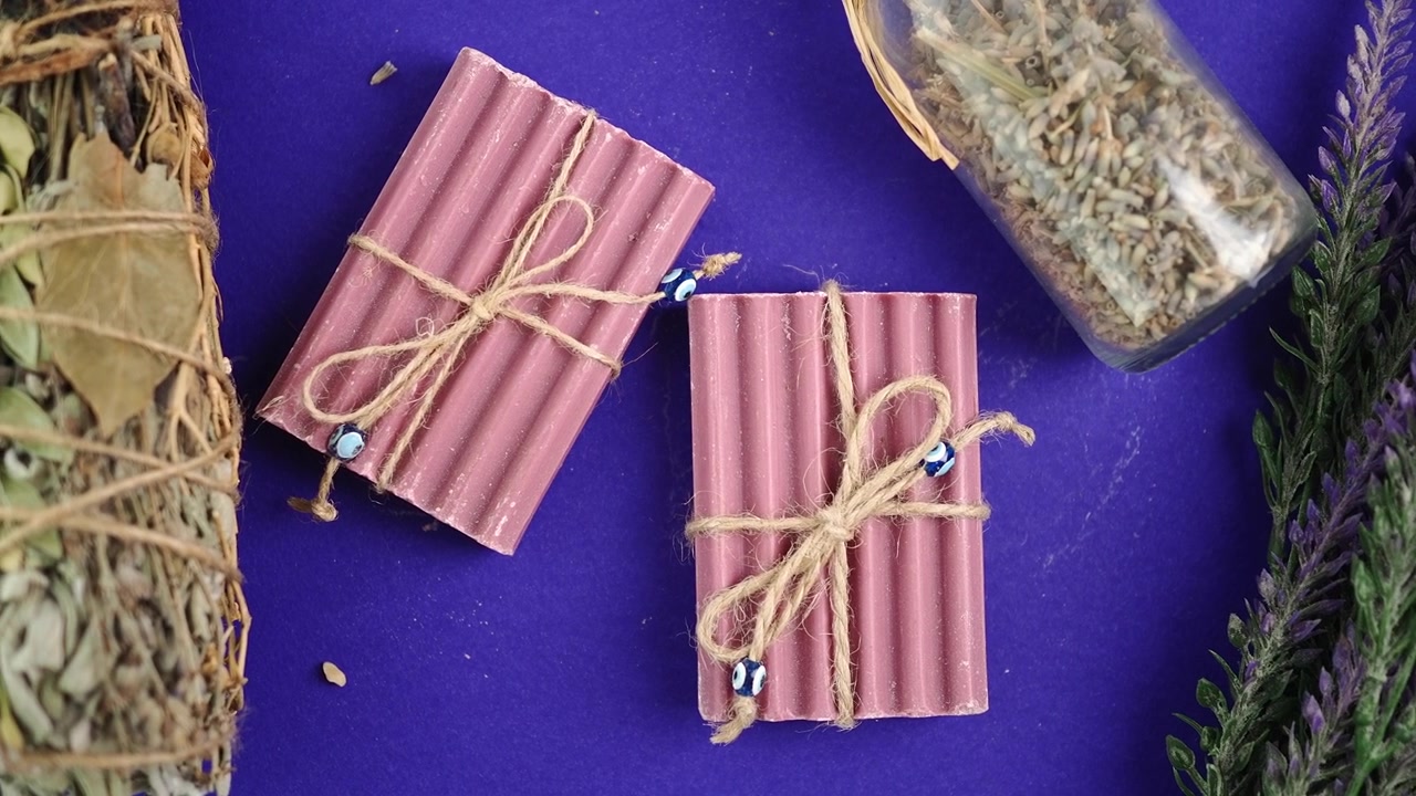 Handmade Lavender Soap Bars with Dried Herbs on Purple Background