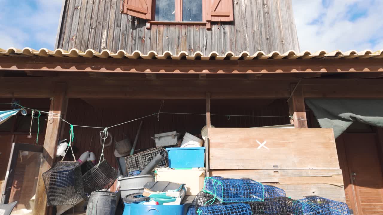 Lobster pots, buckets and other fishing equipment drying and stored under a roof in the fishing harbor of Alvor, Portugal