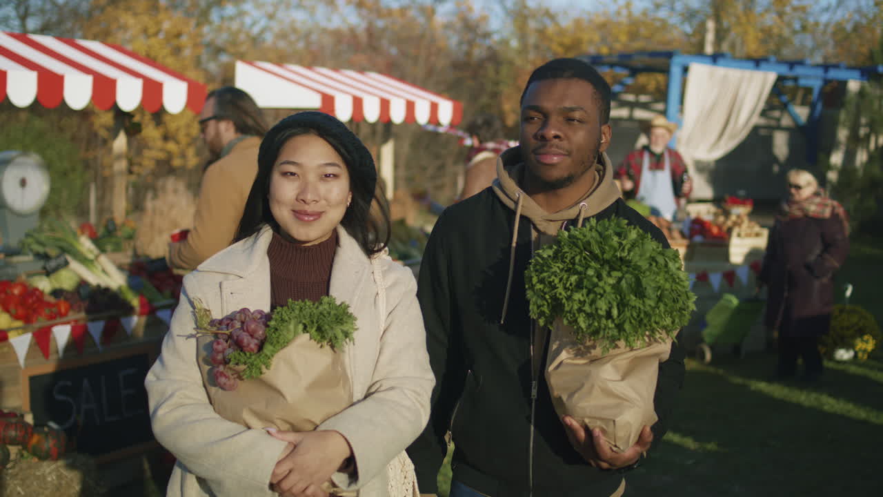 Diverse Couple after Shopping at Farmers Market Diverse Couple Standing with Paper Bags of Vegetables or Fruits Spouses Looking at Camera Smiling People Buy Healthy and Fresh Food on Background Shopping at Local Farmers Market Portrait View