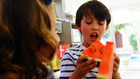 Siblings-having-watermelon-in-kitchen