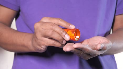 person pouring pills from container into hand