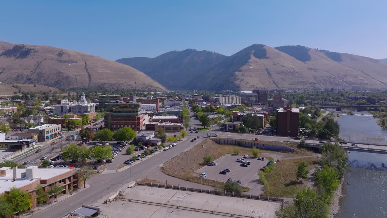 Rapida ascesa aerea che mostra il centro di Missoula, Montana, sul lungofiume, con il ponte sul fiume Clark Fork.