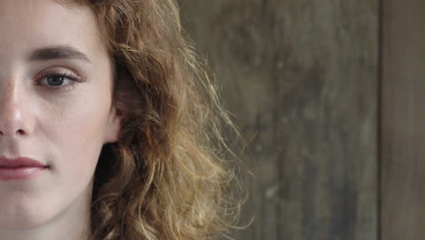 half face portrait of attractive young woman looking at camera calm caucasian red head female beauty on wooden background