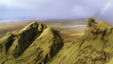 aerial view of rainbow in the mountains, flying over top of the mountain.  drone view of rainbow in the cliff of the mountans, iceland.