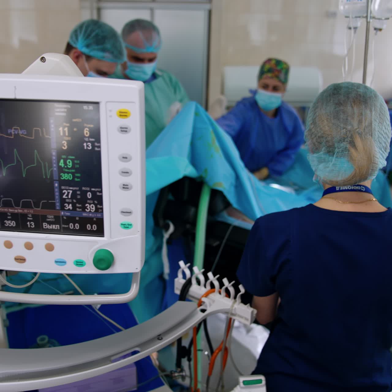 Un anestesista si trova al bancone di consegna. Chirurghi e infermieri eseguono l'operazione. I monitor mostrano i parametri vitali del paziente