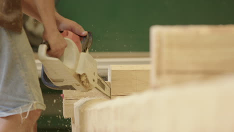 artisan uses chainsaw to cut out dovetail from log during log cabin project