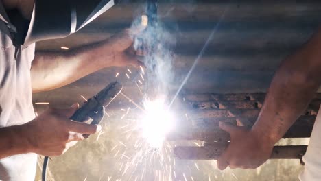 professional welder employing industrial welding machine to put together two pieces of metal creating a metalic structure as part of his daily work at a local small business