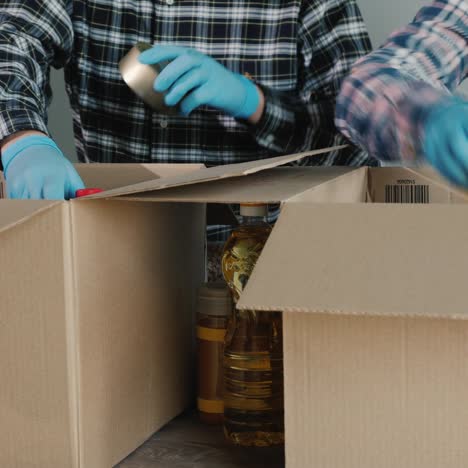 a group of volunteers packs food into cardboard boxes for delivery