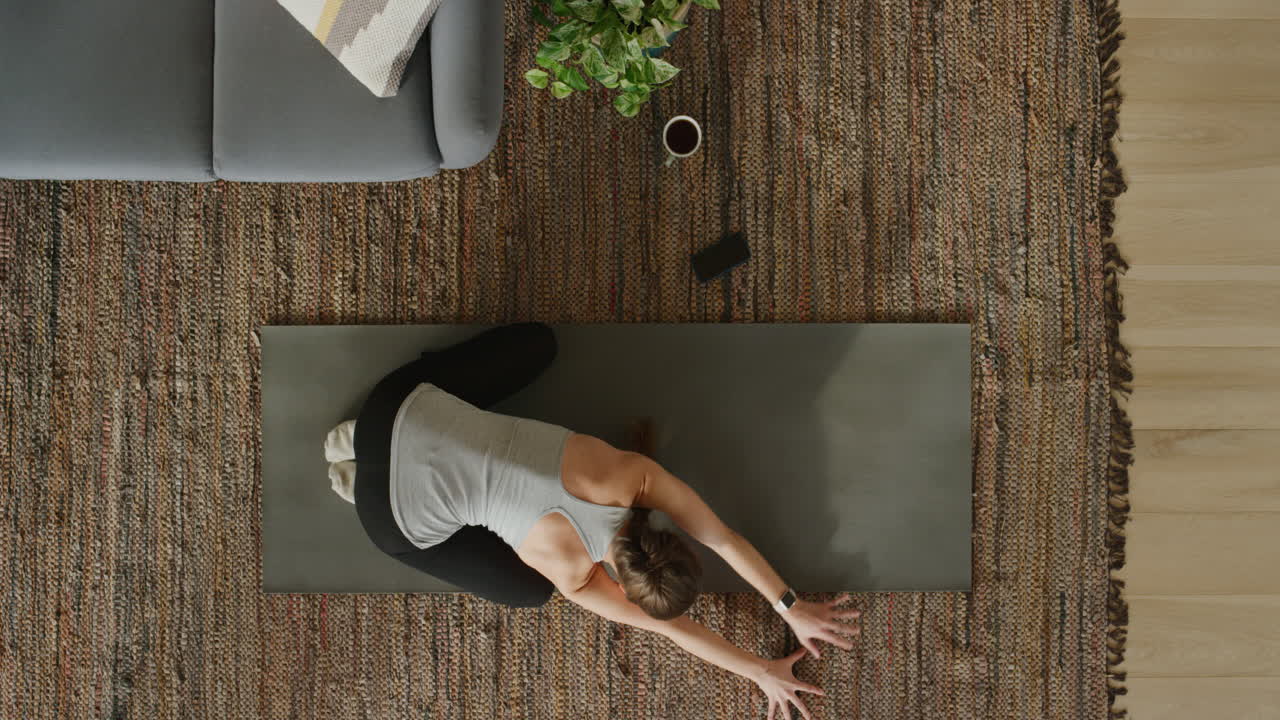 vista superior de una mujer de yoga practicando pose infantil ejercitando un estilo de vida saludable entrenando en casa sobre una colchoneta de ejercicios disfrutando de la meditación de atención plena