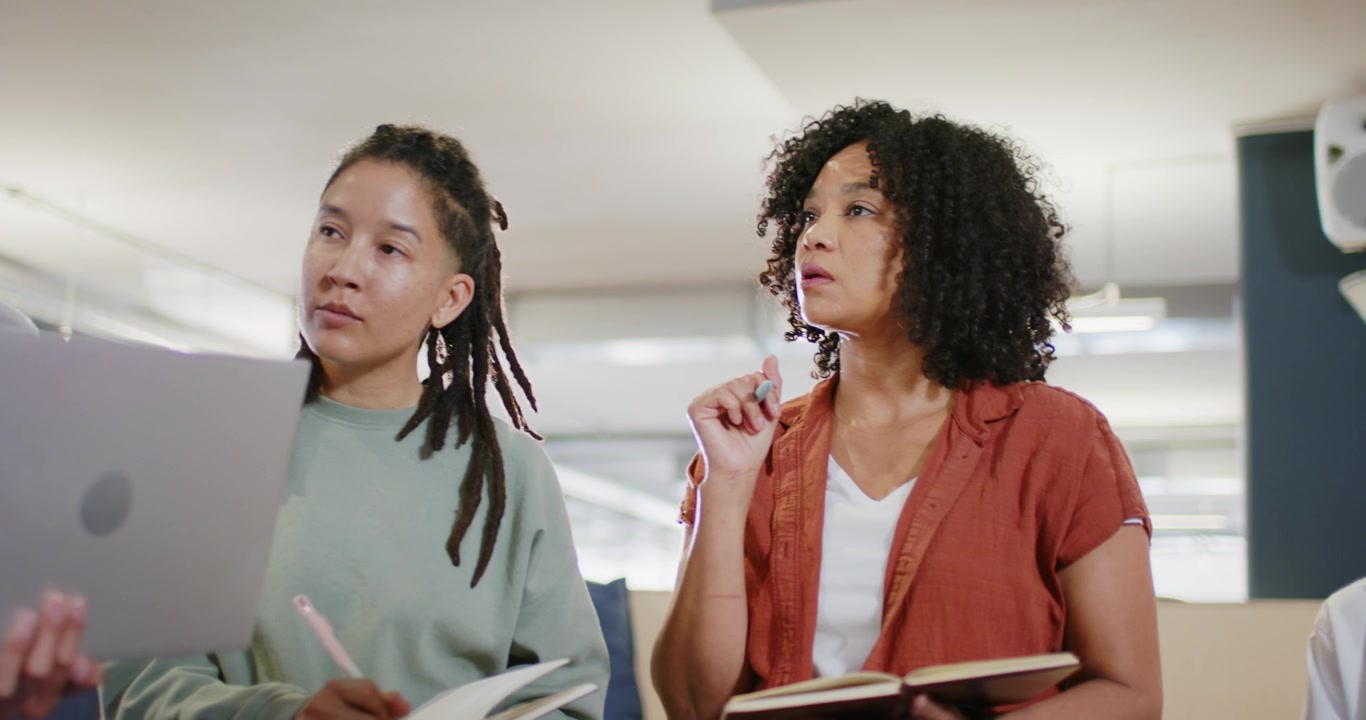 Diverse women in office, curly starting, hijab holding laptop, dreadlocked writing planning notes