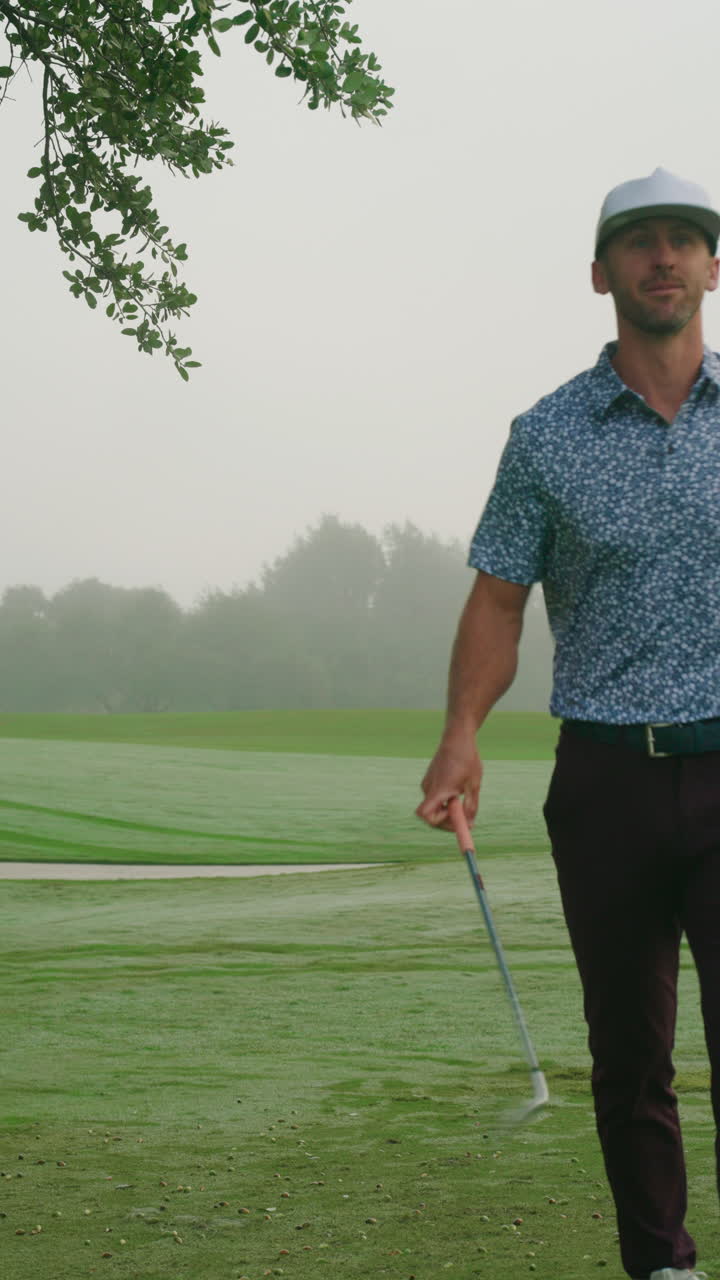 Mutlu bir erkek golfçünün fairway'den demir sopasıyla temiz bir vuruş yaptığı, topu güçlü bir form ve doğal saha ambiyansı ile green'e doğru gönderdiği dikey yaklaşım çekimi. Golfçü gülümsüyor