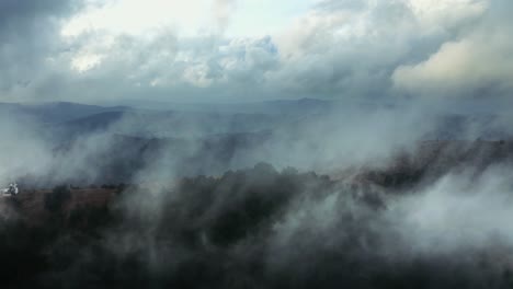 el dron vuela en las nubes en la cima de la montaña