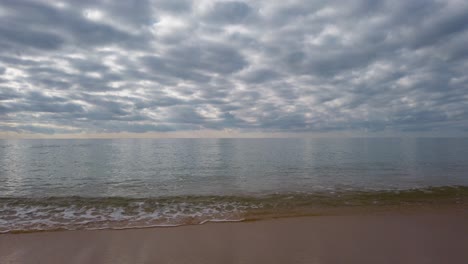 The-sun's-rays-try-to-break-through-the-cumulus-clouds-onto-the-ocean-surf