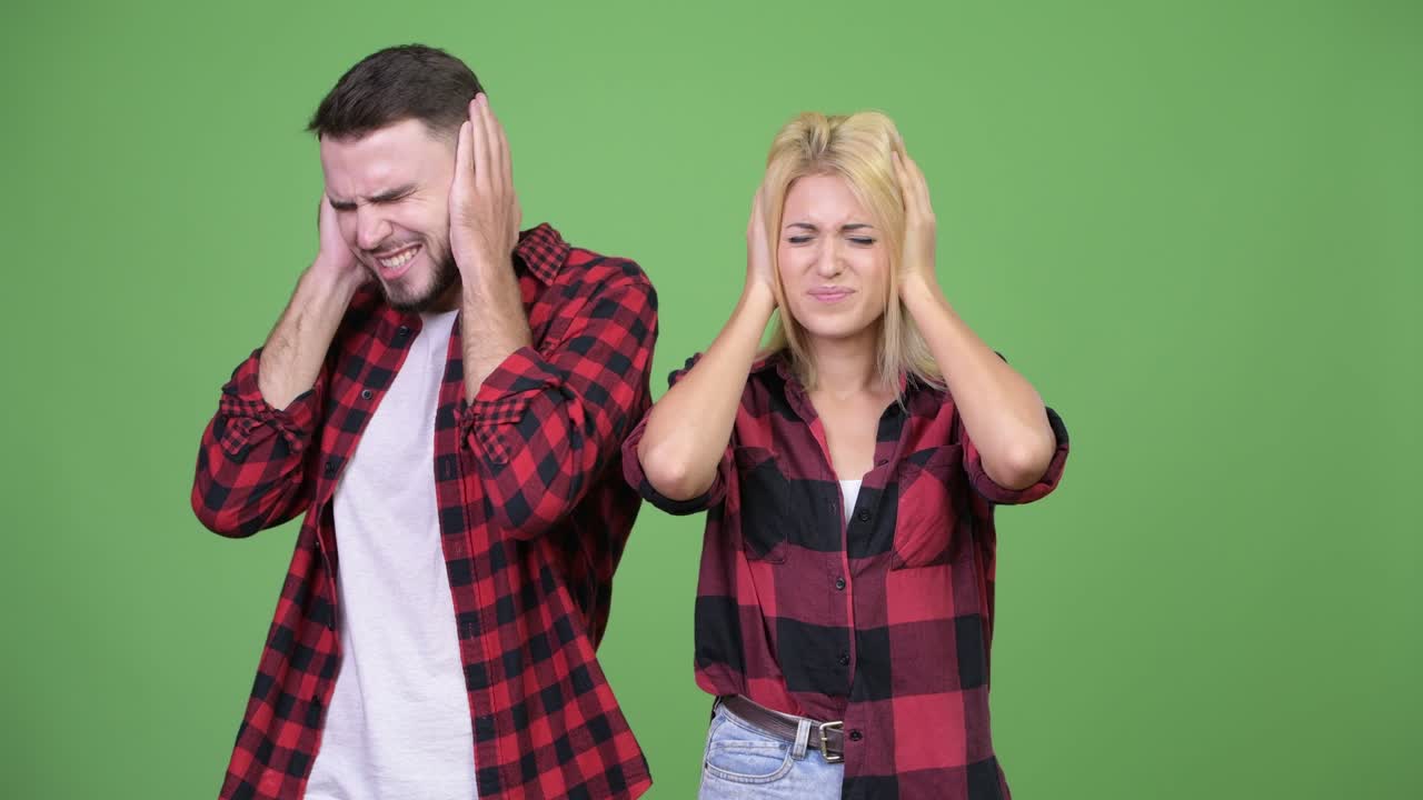 Young couple covering ears from loud noise together