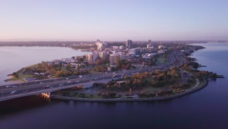 Aerial-view-of-South-Perth-Foreshore-district-with-circular-camera-motion-at-sunrise,-showing-busy-roads,-traffic-and-morning-commute