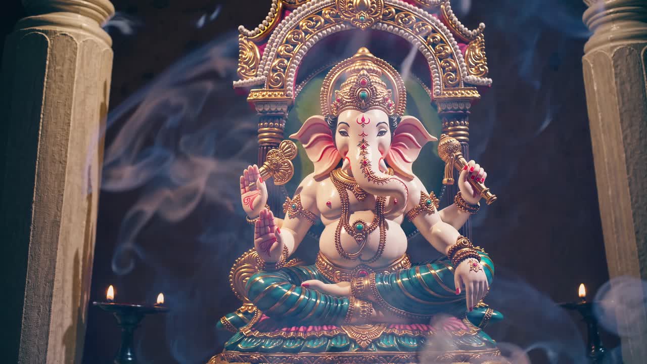 A frontal view of a colorful Ganesha statue, surrounded by incense smoke, creating a serene