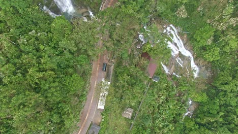 Top-view-shot-from-the-famous-Tamaraw-Falls-from-Oriental-Mindoro,-surrounded-by-tall-trees-and-the-long-curved-highway-in-the-middle,-Philippines