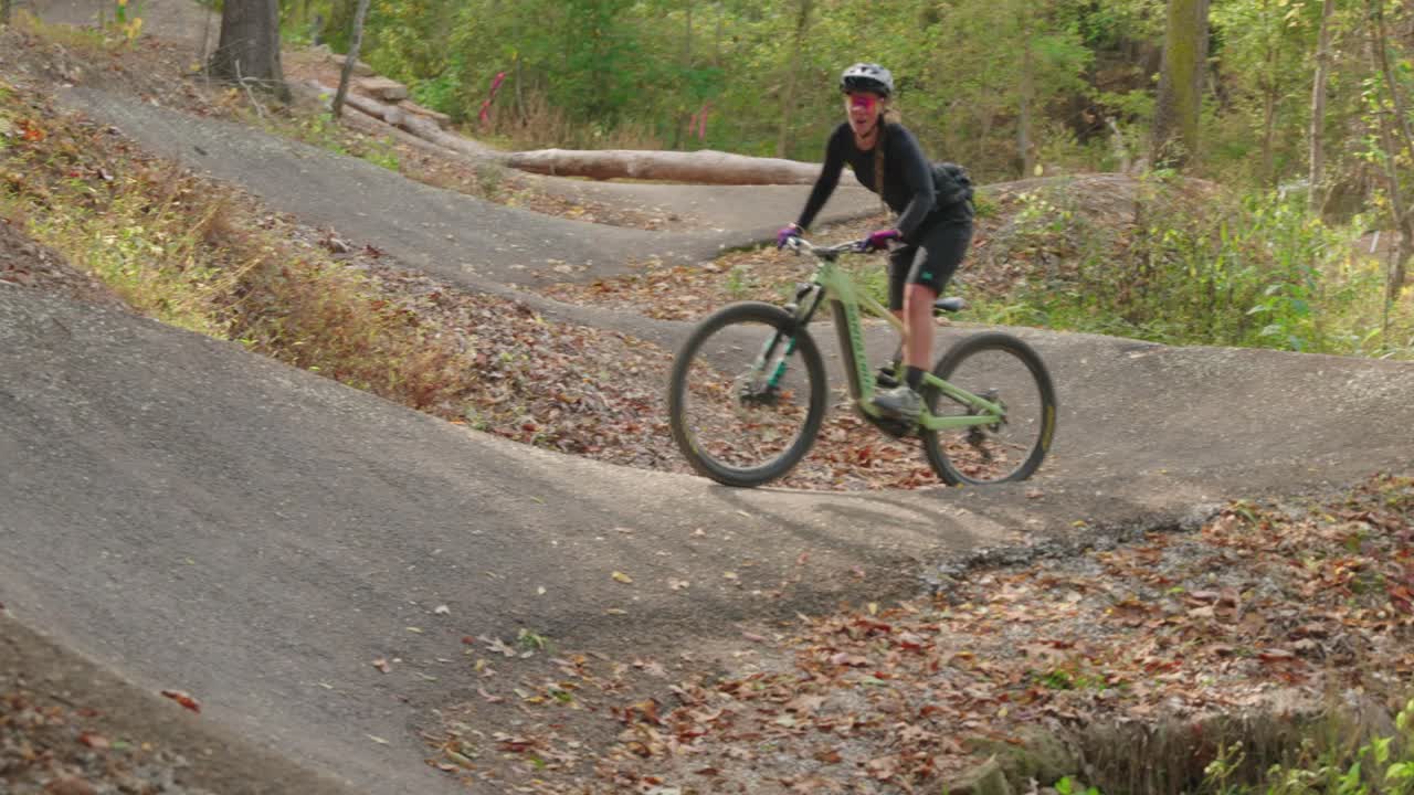 A woman riding mountain bike berms made out of asphalt in bentonville arkansas on her santa cruz ebike