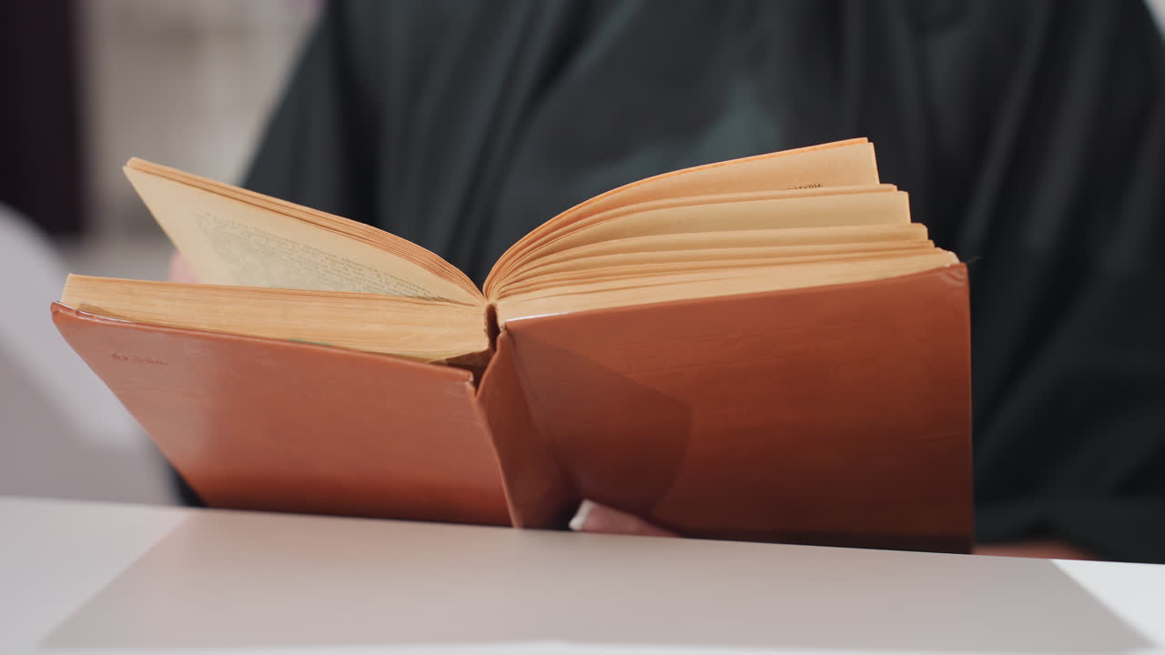 literatura antigua sobre un escritorio, volumen clásico con un delicado pasar de hojas, manuscrito retro apoyado sobre una superficie de madera, libro histórico iluminado por una suave luz natural en un rincón de lectura acogedor