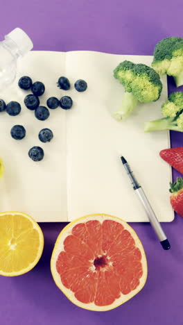 botella de agua, frutas, verduras, cuaderno, bolígrafo y cinta métrica