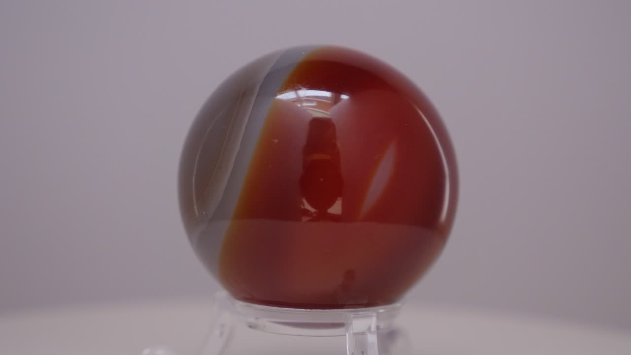 esfera mineral de cristal de ágata girando en una mesa giratoria frente a un fondo blanco