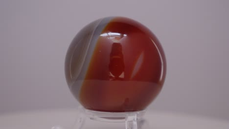 agate crystal mineral sphere rotating on a turn table in front of a white background