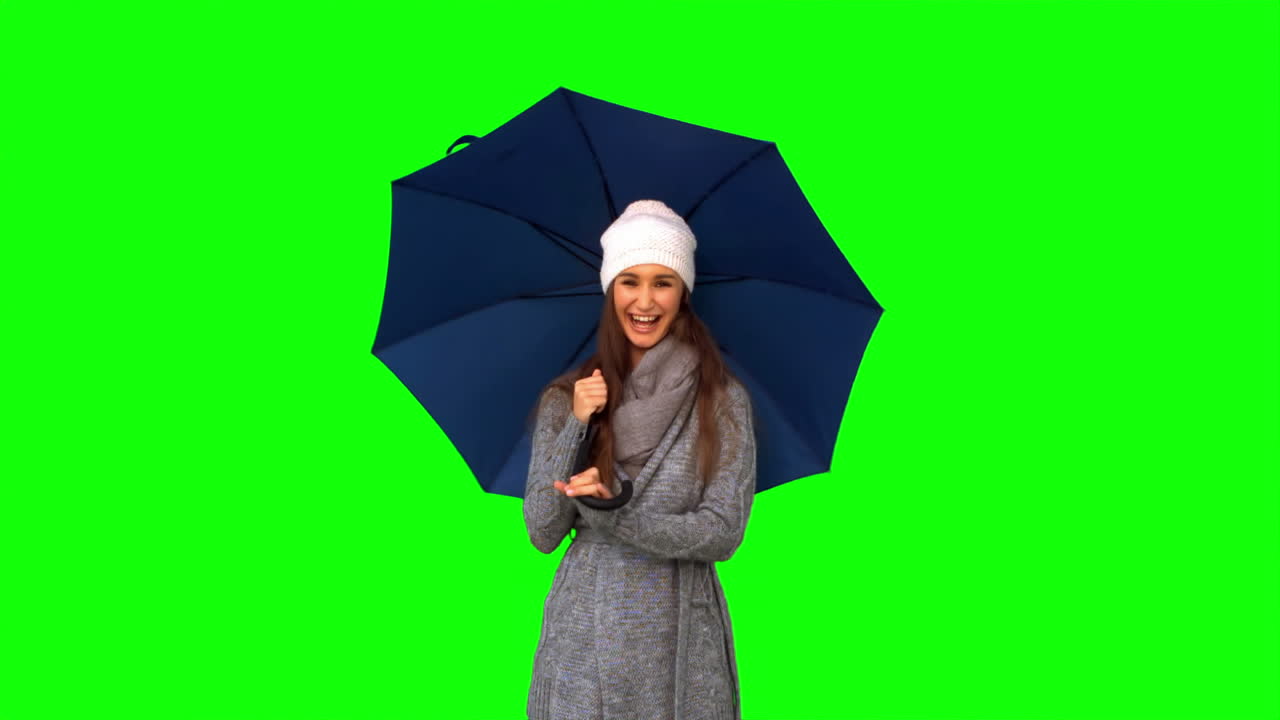 Giovane donna sorridente che gioca con un ombrello