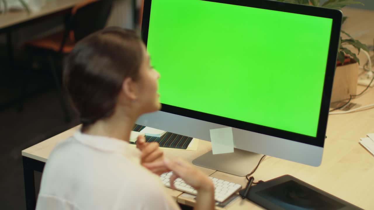 mujer joven llama video en línea en la computadora con pantalla verde en la oficina