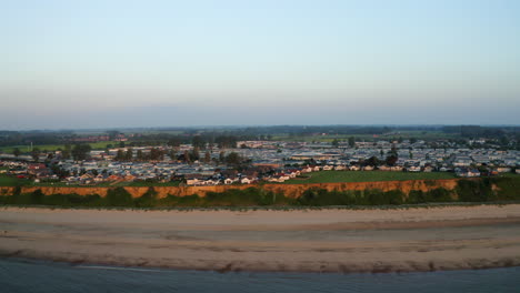 drone aerial footage flying towards a golden sandy beach from out to sea at sunset in norfolk, great britain