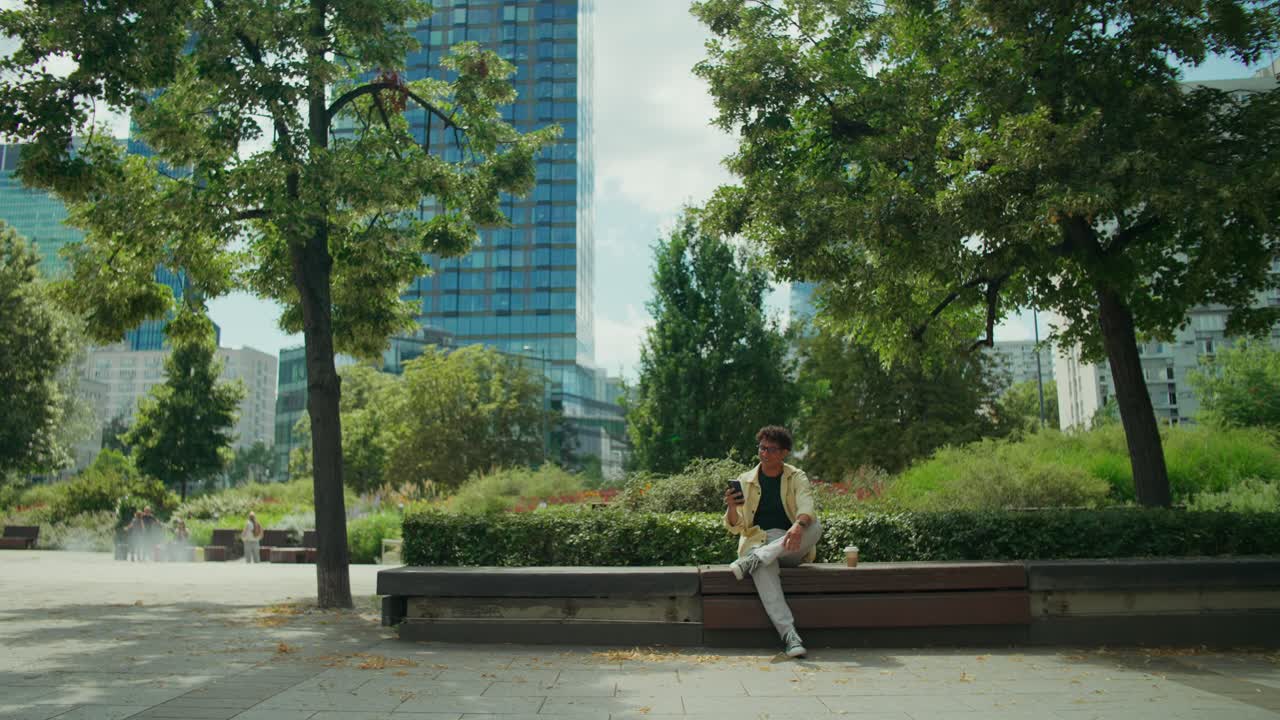 Um homem em um parque com prédios no plano de fundo