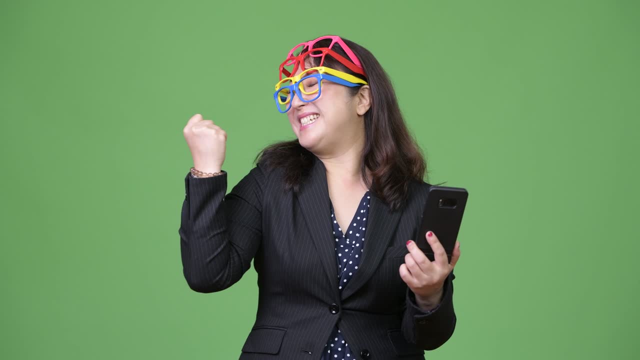 성숙한 아름다운 아시아 사업가 여성은 재미있는 개념으로 많은 안경을 착용하면서 전화를 사용합니다.