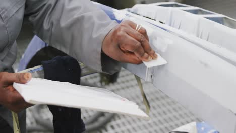 african american female car mechanic painting a body of a car