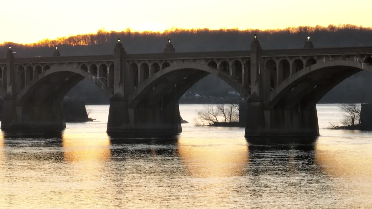 Cinematic rising drone of tranquil Susquehanna River with sun Reflection on water surface and traffic on Columbia&ndash;Wrightsville Bridge with arches
