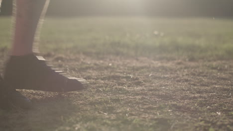 man stretching his legs before a run whilst being silhouetted by the evening sun - ungraded