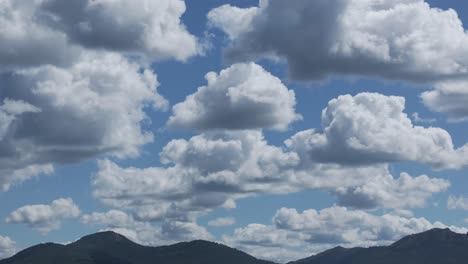 filmando con un dron en 167mm el paso de un gran grupo de hermosas nubes blancas con sombras en las partes inferiores en un sorprendente cielo azul con sus peculiares formas de algodón, la grabación es relajante