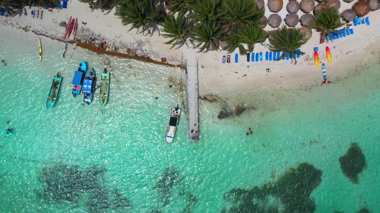 Ripresa cinematografica con drone dall'alto che inizia su un molo per poi salire rivelando la spiaggia del resort a Mahahual, Messico.