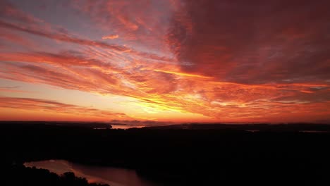 drone shot of the sun setting through a wispy wall of clouds over lake monroe in indiana