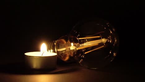 una sola vela de tealight encendida junto a una bombilla de led