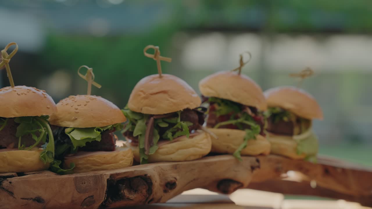 Tempting row of fresh burgers skewered and arranged on natural wood for savory indulgence