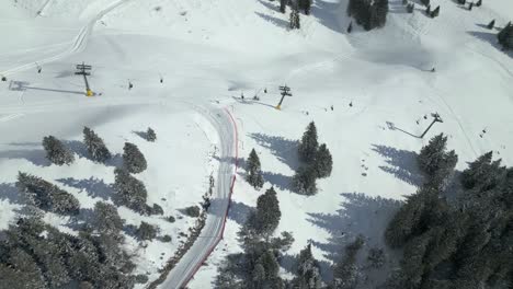 Aerial-drone-pan-shot-from-left-to-right-over-people-going-up-mountain-by-chairlifts-at-Engelberg-Brunni-bahnen-along-the-Swiss-alps-in-Switzerland-on-a-cold-winter-day